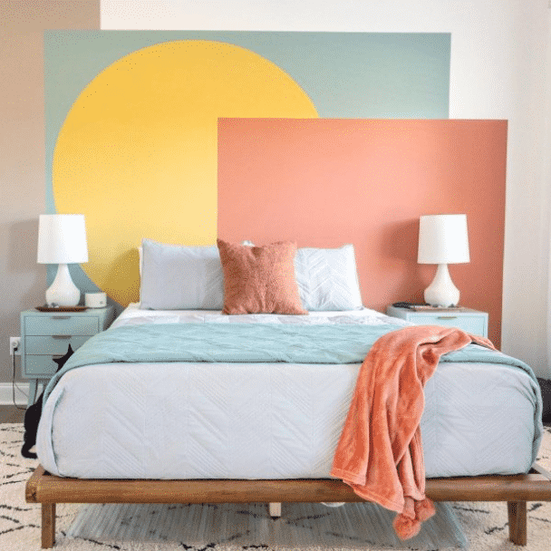 A bedroom with an accent wall made of a few large geometric shapes of different bright colors. Photo credit to @ lelaburris.