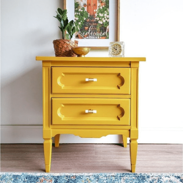 A small side table with two drawers painted a rich yellow. Photo credit to @risforredeemed.